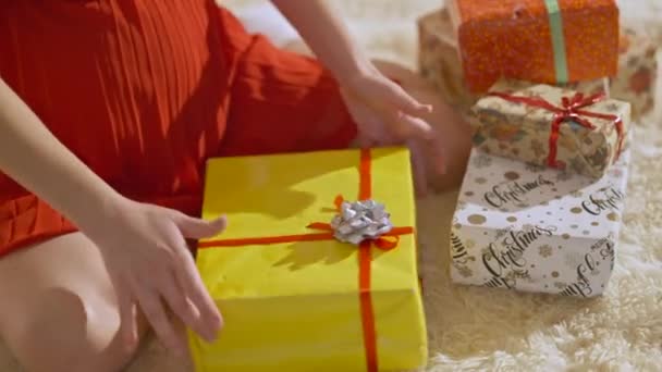 認知できない白人妊娠中の女性がクリスマスの贈り物を家に詰め込んでいます。若いスリムな期待が新年と屋内に座っている腹を愛撫提示します。お祝い事・妊娠. — ストック動画