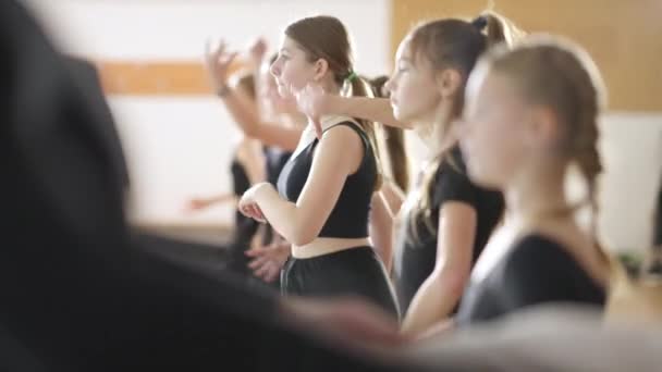 Seitenansicht kaukasischer Mädchen, die Hände in Zeitlupe stehend in der Tanzschule bewegen. Selbstbewusste, talentierte Balletttänzer proben im Tanzstudio drinnen. Geschicklichkeit und Kunstkonzept. — Stockvideo