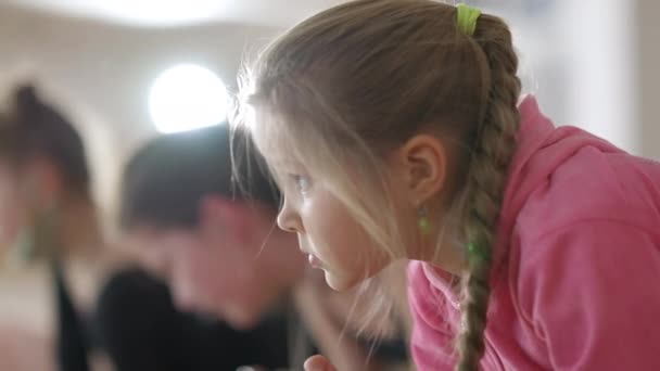Обличчя наполегливої маленької дівчинки з кігтями стоїть на дошці в танцювальній студії перед репетицією. Портрет упевненої кавказької дитячої репетиції в танцювальній школі.. — стокове відео
