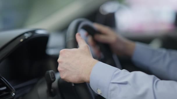 Detailní záběr mužských bělošských rukou na volantu. Nerozpoznatelný úspěšný podnikatel, který si vybral vozidlo v prodejně. Bohatý sebevědomý muž kupující automobil v showroomu. — Stock video