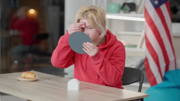 Portret van tiener Aziatisch meisje met problematische huid aanbrengen concealer of make-up foundation zitten aan tafel met handspiegel. Een tiener die gezichtsgebreken verbergt. Problemen met adolescentie. — Stockvideo