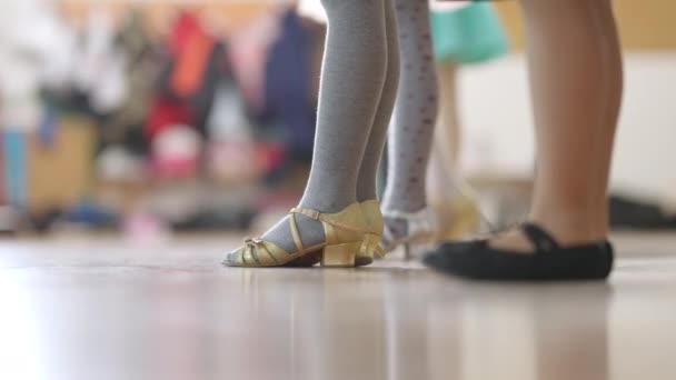 Vista lateral pernas de meninas de pé na escola de dança. Crianças caucasianas irreconhecíveis aprendendo a dançar no estúdio de dança. Ballet e conceito de arte. — Vídeo de Stock