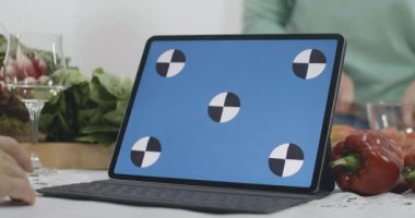 Evdeki mutfakta sağlıklı beslenme yemekleri pişiren bulanık yaşlı kadınların olduğu mavi ekranlı dizüstü bilgisayara yakın çekim. İnternet sitesinden internet tarifi kullanan tanınmayan Kafkasyalı emekliler. Sinema 4k ProRes Merkezi.