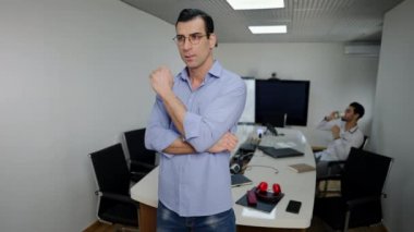 Orta Doğulu düşünceli bir adam gözlüklerini indirip kameraya sersemlemiş bir yüz ifadesiyle bakıyor. Ofiste poz veren kendine güvenen yakışıklı iş adamının portresi..