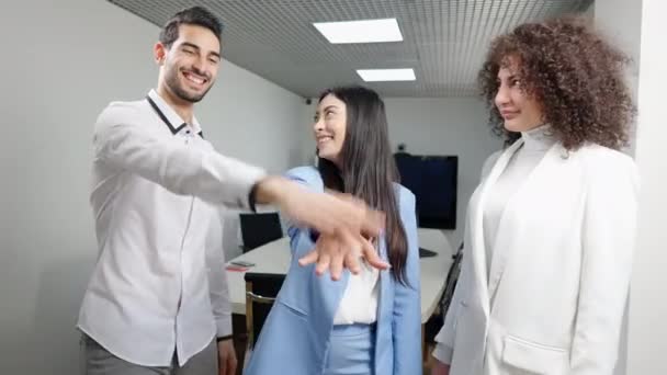 Rire positif jeunes collaborateurs multiraciaux millénaires empilant les mains dans le bureau. Heureux collègues caucasiens, asiatiques et du Moyen-Orient joyeux réjouissant le succès à l'intérieur. Style de vie professionnel. — Video