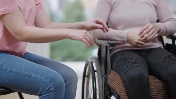 Jeune femme paralysée méconnaissable et amie tenant la main assise à l'intérieur. Slim dame empathique caucasienne réconfortant ami paralysé déprimé à la maison. Soutien et handicap. — Video