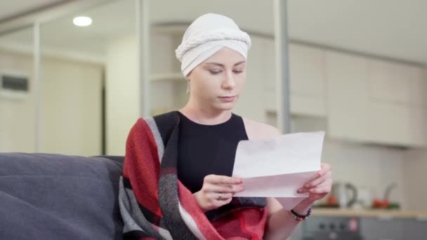 Stressato sconvolto giovane donna lettura lettera con cattive notizie, toccando la testa e sospirando. Ritratto di triste signora magra caucasica infelice seduta sul divano a casa all'interno. Tristezza e problemi. — Video Stock