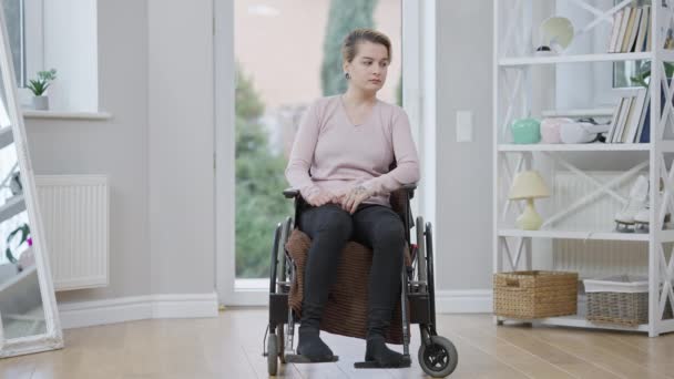 Portrait large de la jeune femme handicapée caucasienne assise en fauteuil roulant pensant. Triste invalide à la maison. Concept de handicap et de désespoir. — Video