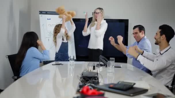Orang-orang bisnis multietnis yang ceria menari bersenang-senang di kantor dengan gadis kecil yang menawan memegang boneka beruang. Pria dan wanita riang yang gembira menikmati gaya hidup di dalam ruangan. — Stok Video