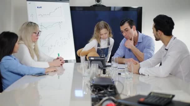 Génie petite fille caucasienne projet de planification avec l'équipe multiraciale adulte au bureau. Portrait d'un enfant patron discutant de démarrage avec des adultes du Moyen-Orient et d'Asie à l'intérieur. Drôle d'affaire. — Video