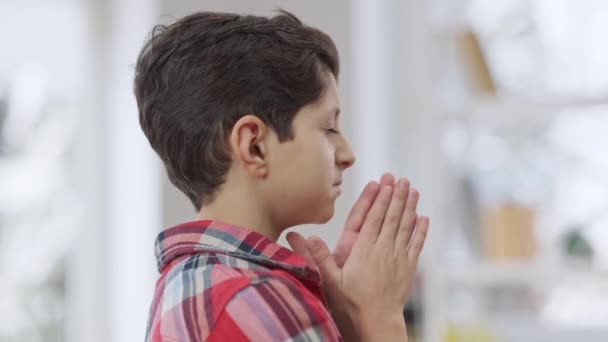옆은 양손 이 꽉 쥐고 기도하고 있는 작은 중동 소년의 근접 사진이다. 신께 기도하는 매력적 인 어린 아이의 모습. 믿음 과 생활 방식의 개념. — 비디오