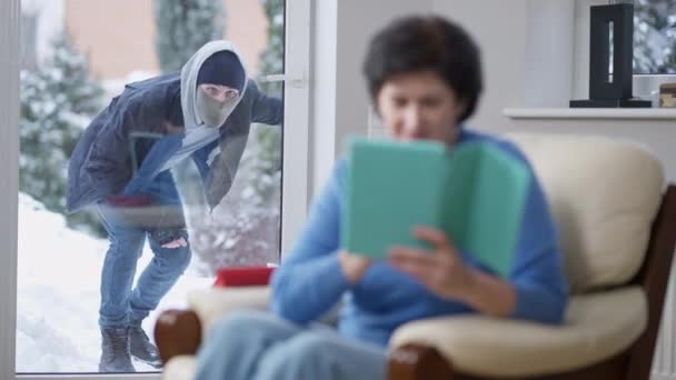 Unfortunate thief looking inside house through glass door as blurred woman turning and noticing burglar running away. Young Caucasian masked robber leaving wealthy house. Victim attentiveness. — Stock Video