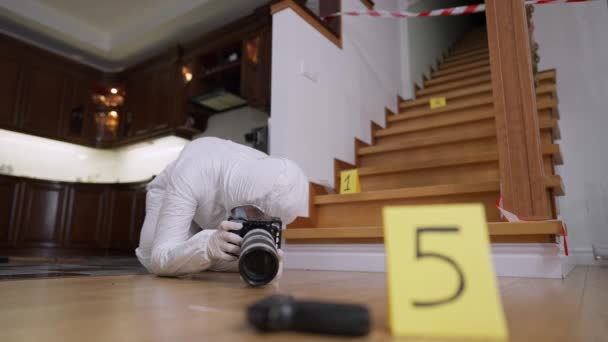 Wide shot of professional concentrated forensic scientist taking photos of clues at crime scene. Portrait of focused Caucasian woman in uniform photographing evidence of robbery or murder indoors. — Stock Video