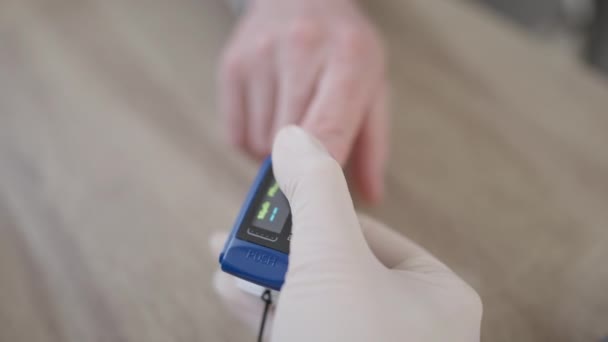 Close-up van verpleegkundige hand drukken knop op pulsoximeter meten zuurstofverzadiging niveau van mannelijke patiënt. Een vrouw die een medische test doet voor een blanke man. Geneeskunde en gezondheidszorg. — Stockvideo