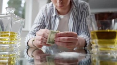 Önündeki cam masada alkol ve beyaz pudrayla dolar banknotları yuvarlayan tanınmamış genç adam. Bin yıllık Kafkasyalı bağımlısı. İçerde içki içiyor ve uyuşturucu kokluyor. Bağımlılık kavramı.