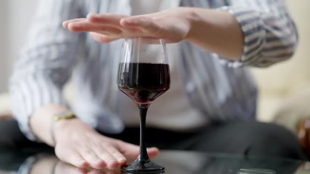 Mano masculina que cubre el vidrio con vino tinto de pie en la mesa de vidrio. Un joven caucásico irreconocible luchando contra la adicción al alcohol. Símbolo de recuperación. — Vídeo de stock