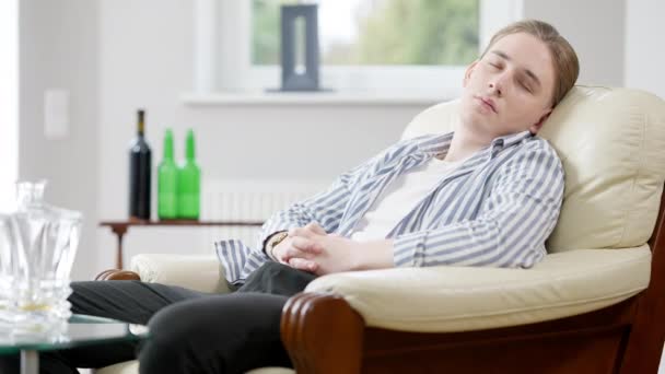 Porträt eines betrunkenen, entspannten Mannes, der zu Hause auf einem Sessel schläft. Junge kaukasische Suchtkranke schlafen drinnen. Sucht- und Erschöpfungskonzept. — Stockvideo