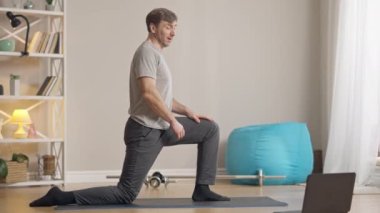 Erkek Yogi 'nin laptopta rahatlama egzersizi yaparken yan görüntüsü. Kendine güveni tam, orta yaşlı, beyaz bir adamın internet günlüğünde çalıştığı geniş bir çekim. Spor ve yoga konsepti.