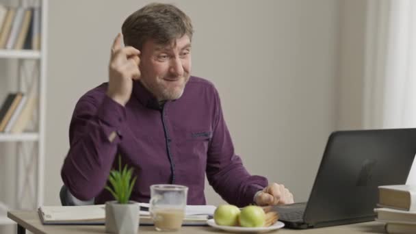 Un hombre reflexivo mostrando que tengo un gesto de idea y anotando en papel. Retrato de emocionado hombre de negocios caucásico de mediana edad feliz que tiene inspiración sentado en el ordenador portátil en el interior. Trabajo en casa. — Vídeos de Stock