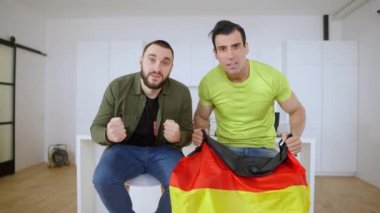 Neşeli Alman spor fanatikleri içeride televizyon izleyen favori takımın zaferini kutluyorlar. Heyecanlı Orta Doğulu ve Kafkas erkekleri oturma odasında tezahürat yapıyor. Kazanan konsept.