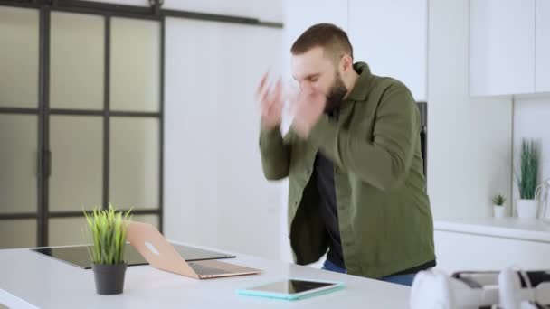 Stressed Caucasian man messaging online on laptop and holding head in hands. Portrait of overwhelmed businessman or CEO in kitchen at home. Working from home and business stress. — Vídeo de Stock