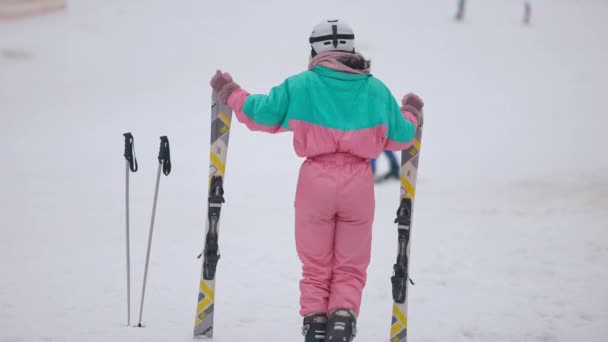 Bakåt se bred bild av smal ung kvinna i skiddräkt dansar i slow motion på skidorten. Glad glad kaukasisk turist njuter vintern fritid på semester. Lycka och turism. — Stockvideo