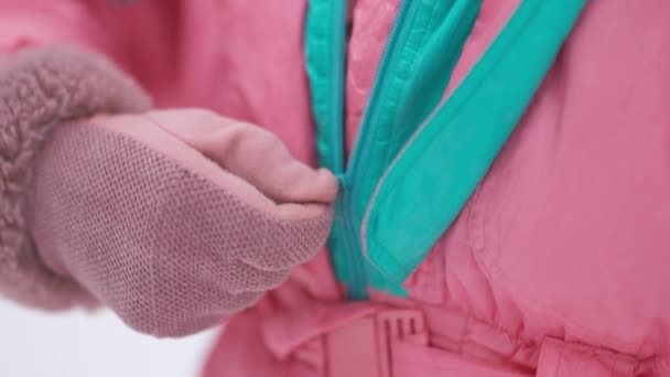 カメラは屋外で女性の手ジッピングスキースーツに従います。スキー場で服を着るミトンの認識できない若い女性。冬の休暇と観光のコンセプト. — ストック動画