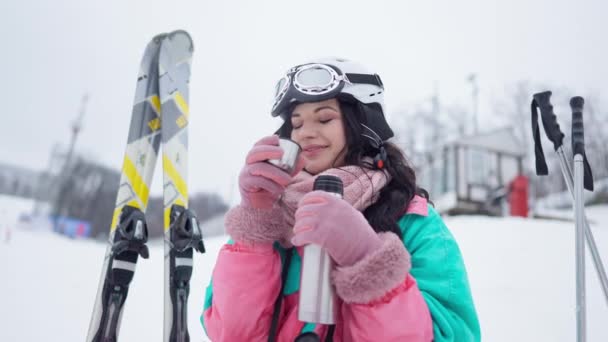 Mellanslag av glada leende ung kvinna dricka välsmakande te utomhus på vinterdagen. Porträtt av nöjd kaukasisk kvinnlig turist njuter av varm dryck på semesterorten. — Stockvideo