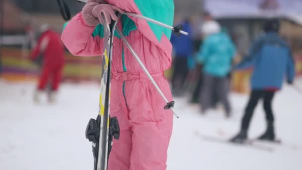 Femeia subțire de nerecunoscut în picioare cu schiuri și stâlpi de schi în aer liber. O tânără turistă se odihneşte în staţiunea de schi în ziua de iarnă. Sporturi de schi și vacanțe . — Videoclip de stoc