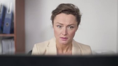 İnternette dizüstü bilgisayarda çalışan endişeli beyaz kadının portresi ofiste oturuyor. Güzel beyaz kadın çalışan, iş yerinde kapalı alanda. İş ve yaşam tarzı.