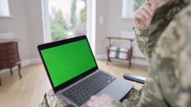 Dizleri yeşil ekranlı bir dizüstü bilgisayar. Kapalı alanda tanınmayan Kafkasyalı bir asker. İnternette sörf yapan yetişkin bir asker ya da gazi ya da evde mesajlaşan biri. Modern teknolojiler, kromakey.