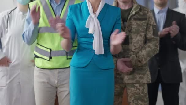 Unrecognizable Caucasian stewardess, soldier, builder, doctor and businessman clapping. Group of happy people of different professions standing indoors. Occupation and diversity. — Stock Video