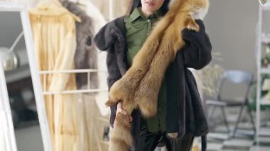Moda dükkanında kırmızı tilki kürkü deneyen kendine güveni olmayan şık bir kadın. Kadın müşteri içeride aksesuar seçiyor. Lüks ve zengin yaşam tarzı konsepti.