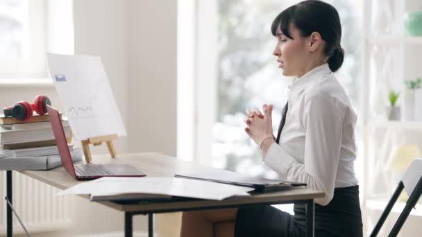 Vista laterale di ansioso preoccupato donna caucasica parlando in video chat online. Giovane impiegata stressata che comunica con colleghi. Tecnologie wireless e stile di vita aziendale. — Video Stock