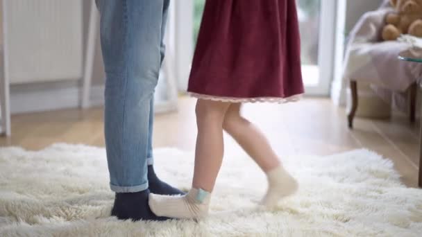 Πόδια μικρού κοριτσιού να πατάνε σε αντρικά πόδια και να χορεύουν. Άγνωστη Καυκάσια κόρη χορεύει με τον πατέρα της μέσα στο σπίτι. Οικογενειακή σχέση και έννοια αναψυχής. — Αρχείο Βίντεο