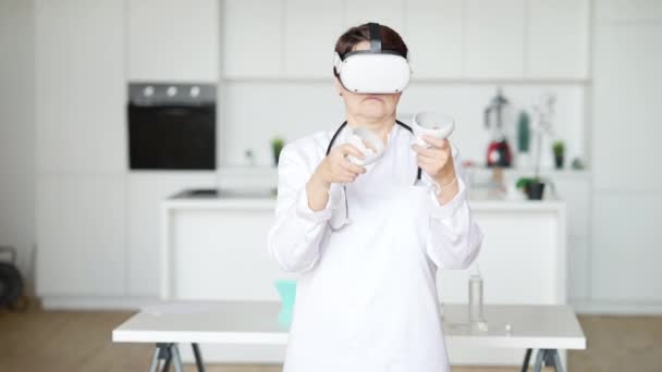 Plan médian d'une femme médecin caucasienne concentrée utilisant un casque VR pour l'entraînement. Femme moyenne caucasienne professionnelle sérieuse pratiquant dans la réalité augmentée à l'intérieur. Technologies modernes. — Video