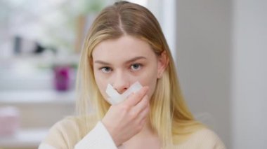 Stresli sinirli bir kadının portresi. Ağzından bandı çıkarıyor ve kameraya bakarak bağırıyor. Öfkeli depresyondaki beyaz kadın serbest kalıyor. Ayrımcılık ve özgürlük kavramı.