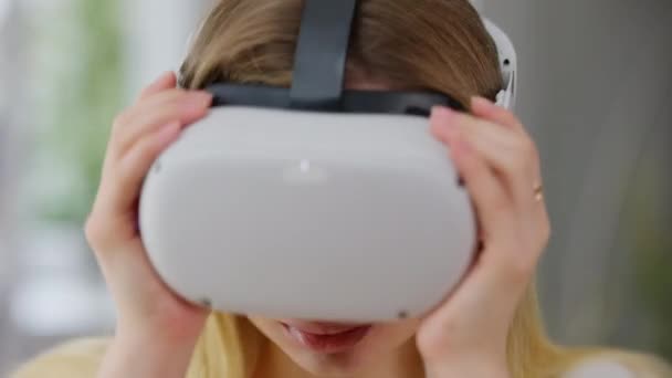 Imagen de la encantadora mujer joven quitándose los auriculares VR mirando a la cámara sonriendo. Primer plano retrato de la señora caucásica feliz sin preocupaciones posando en casa en el interior después de los juegos en línea. Estilo de vida moderno. — Vídeo de stock