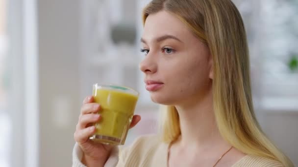 Närbild porträtt av glad smal vacker kvinna dricka vitamin frukt smoothie inomhus. Leende charmig passform Kaukasiska dam njuter hälsosam dryck hemma på morgonen. Välmående och välbefinnande. — Stockvideo