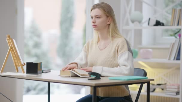 Una joven ciega concentrada leyendo un libro de Braille en casa. Retrato de una hermosa mujer caucásica discapacitada disfrutando de hobby en el interior. Concepto de discapacidad y necesidades especiales. — Vídeo de stock