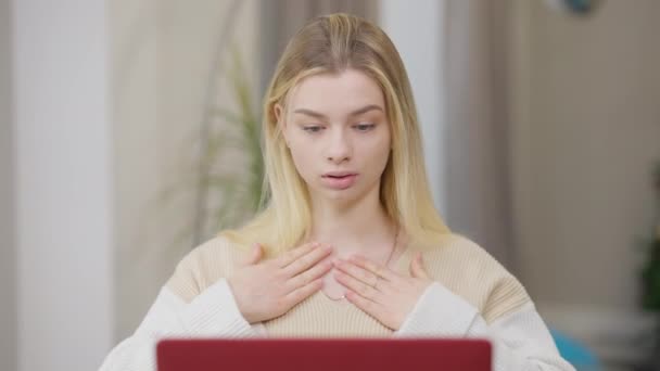 Portrét mladé ženy, která se učí znakovou řeč on-line gestikuluje a dívá se na monitor notebooku. Soustředěná krásná běloška, která se dívá na video lekci vevnitř. Koncept hluchoty. — Stock video