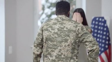 Kafkasyalı, gözleri kapalı bir kadına çiçek buketiyle yürüyen Afrikalı Amerikan askerinin arka görüntüsü. Sevgi dolu koca, heyecan dolu güzel eş eve dönüyor. Buluşma ve aşk.