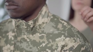 Tanımlanamayan Afro-Amerikan askeri kamuflajlı, bulanık beyaz bir kadının elini omzuna koyduğu yakın plan. Üzgün genç acemi sevgili eşini ya da kız arkadaşını terk ediyor..