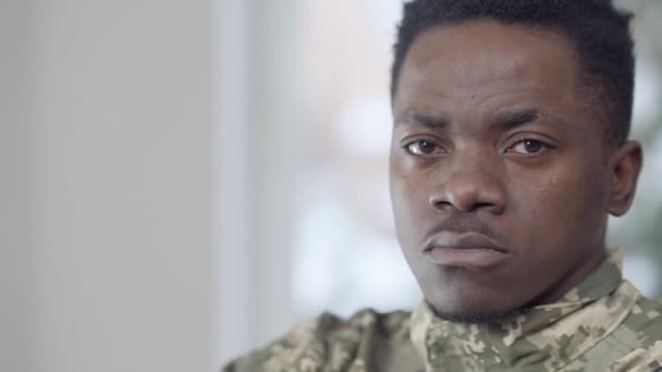 Detailní záběr seriózního afroamerického rekruta, jak se dívá do kamery. Portrét statečného sebevědomého vojáka, jak pózuje uvnitř. Koncept povinného a obranného průmyslu. — Stock video