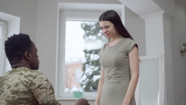 Portrait of excited young gorgeous Caucasian woman saying yes to African American military man proposing. Happy cheerful beautiful girlfriend hugging loving boyfriend smiling. Engagement concept. — Stock Video