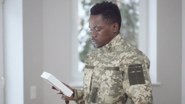 Zijaanzicht portret van overstuur jonge Afro-Amerikaanse militair kijken naar beeld denken. Droevige knappe rekruut verloren vriend op oorlog die herinneringen oproept. Verdriet en defensiedienst. — Stockvideo