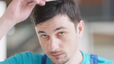 Neşeli, kendine güvenen genç müteahhit, kameraya gülümseyen bir şapka takıyor. Kapalı mekanda poz veren yakışıklı beyaz adamın yakın plan portresi..