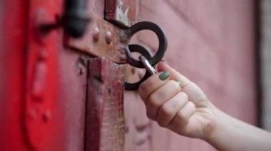 Dışarıdaki endüstriyel kapıyı kilitleyen kadın eli yakın plan. Kenar mahallelerdeki kapalı imalat sahasında tanınmayan beyaz bir genç kadın. Şehir konsepti.