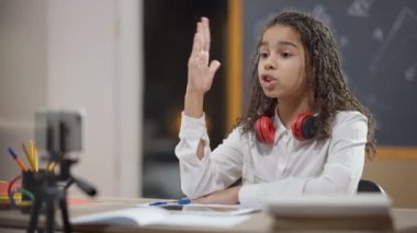 Heyecanlı Afrikalı Amerikalı öğrenci akıllı telefon kullanarak internetten el kaldırıyor. Koronavirüs kilitlenmesiyle öğrenen zeki bir kız. Covid eğitim ve zeka kavramı.