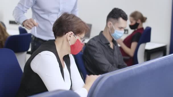 Konzentrierte kaukasische Männer und Frauen mit Covid-Gesichtsmasken, die im Büro als professioneller männlicher CEO arbeiten und Mitarbeitern bei der Geschäftsstrategie zur Coronavirus-Pandemie helfen. — Stockvideo